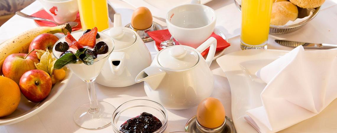 Ricca colazione con succo, tè, panini, frutta, marmellata e yogurt con frutti di bosco.