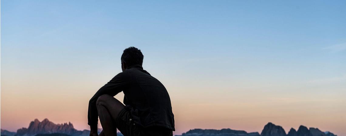 Ein Mann beobachtet den Sonnenaufgang in den Bergen